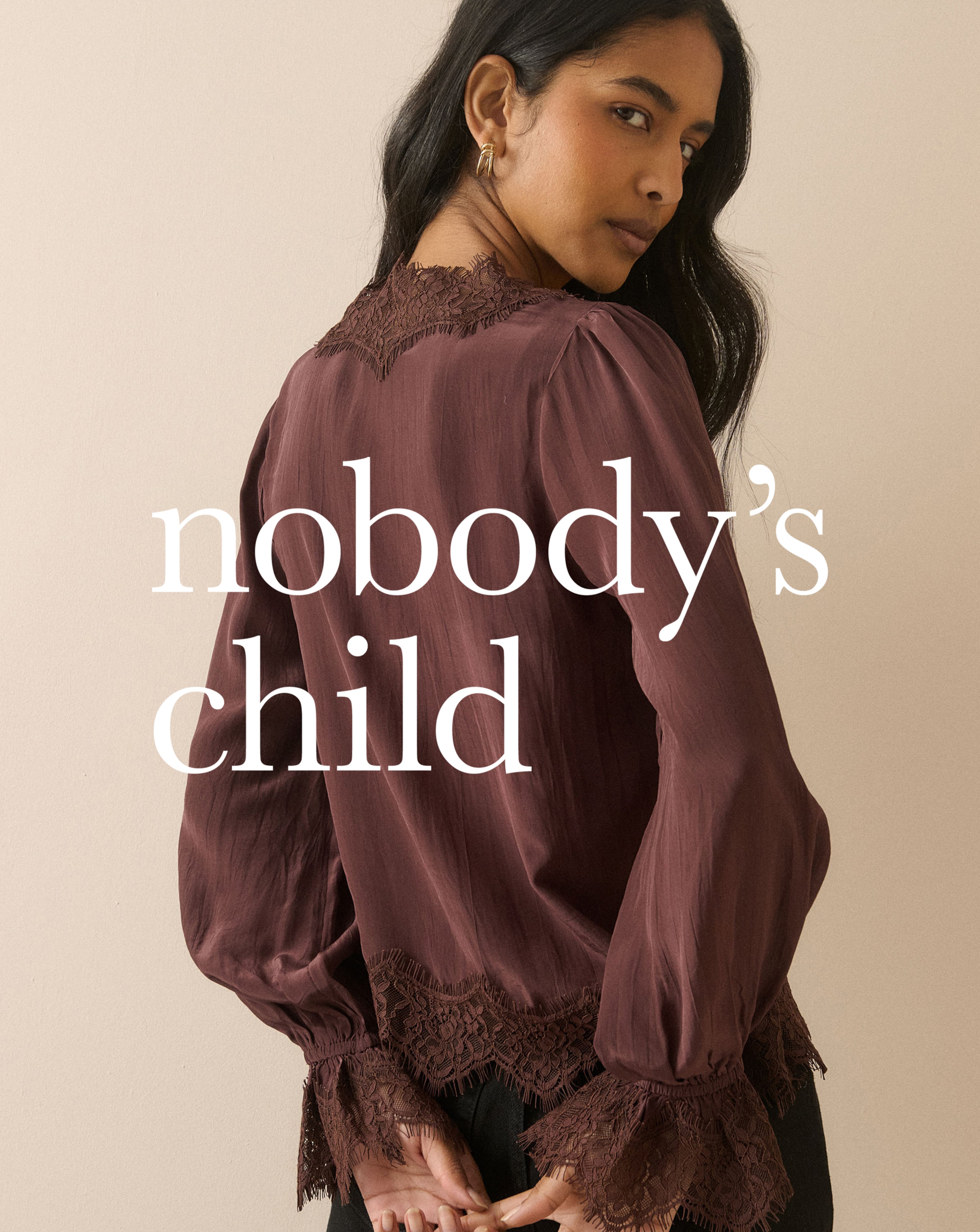 Person wearing a burgundy lace-trim blouse with gathered sleeves, with the “Nobody’s Child” logo overlaid on the image.