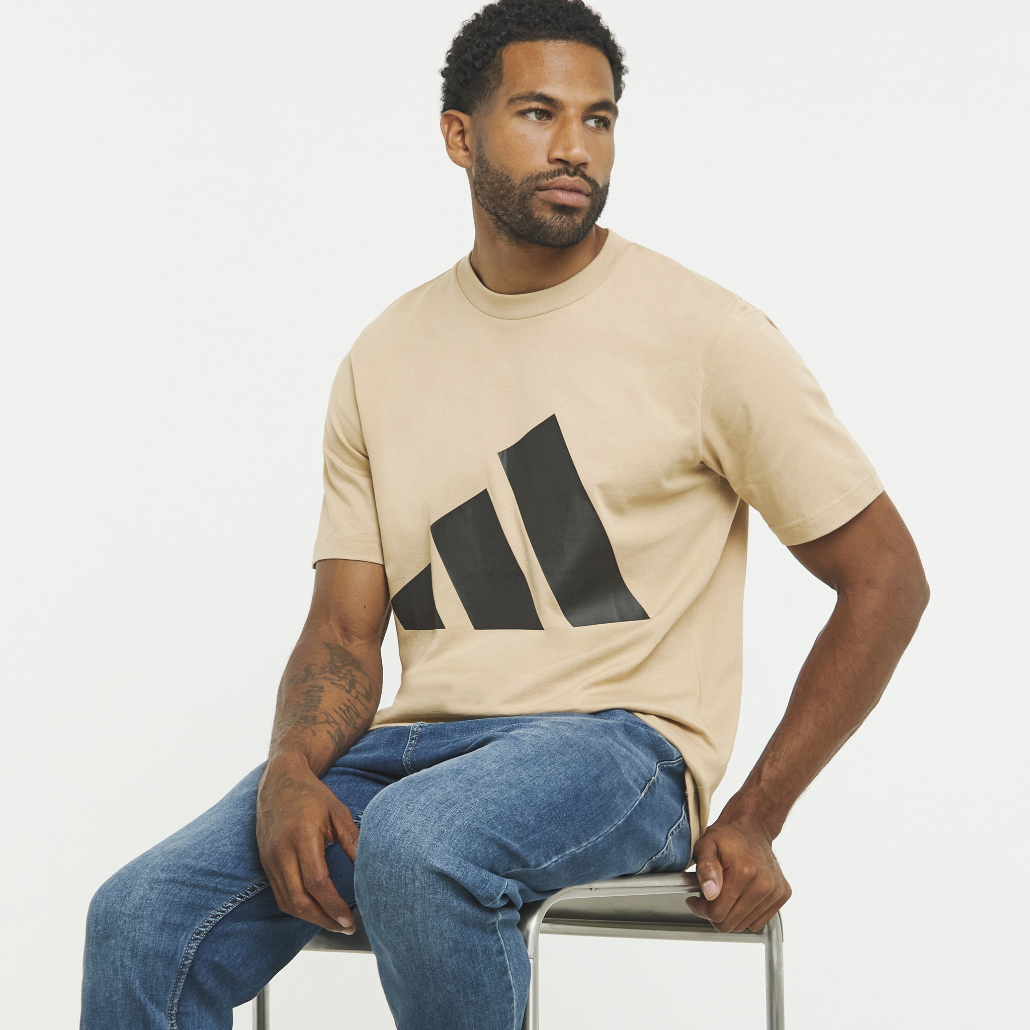 Man on seat with beige addidas t-shirt