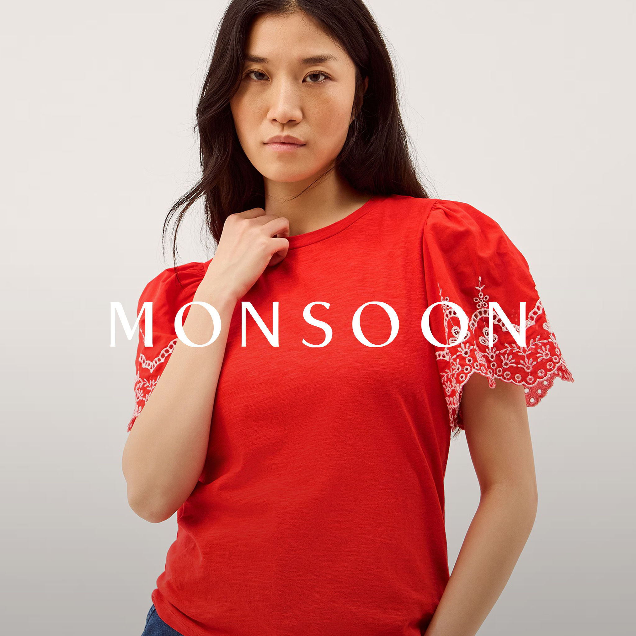 Person wearing a red short‑sleeve top with embroidered lace details on the sleeves.