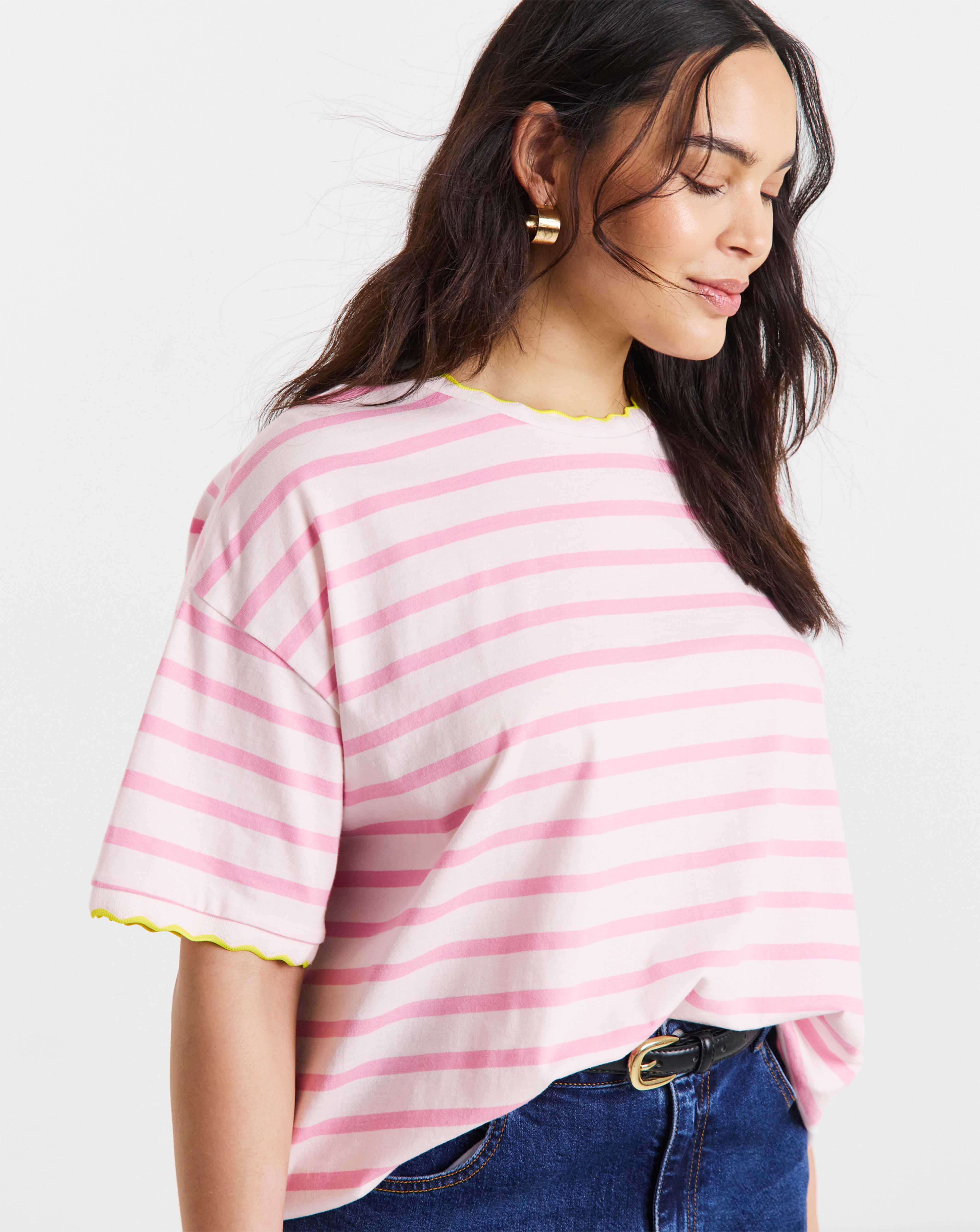 Person wearing a Simply Be pink stripe scallop t-shirt and blue jeans.