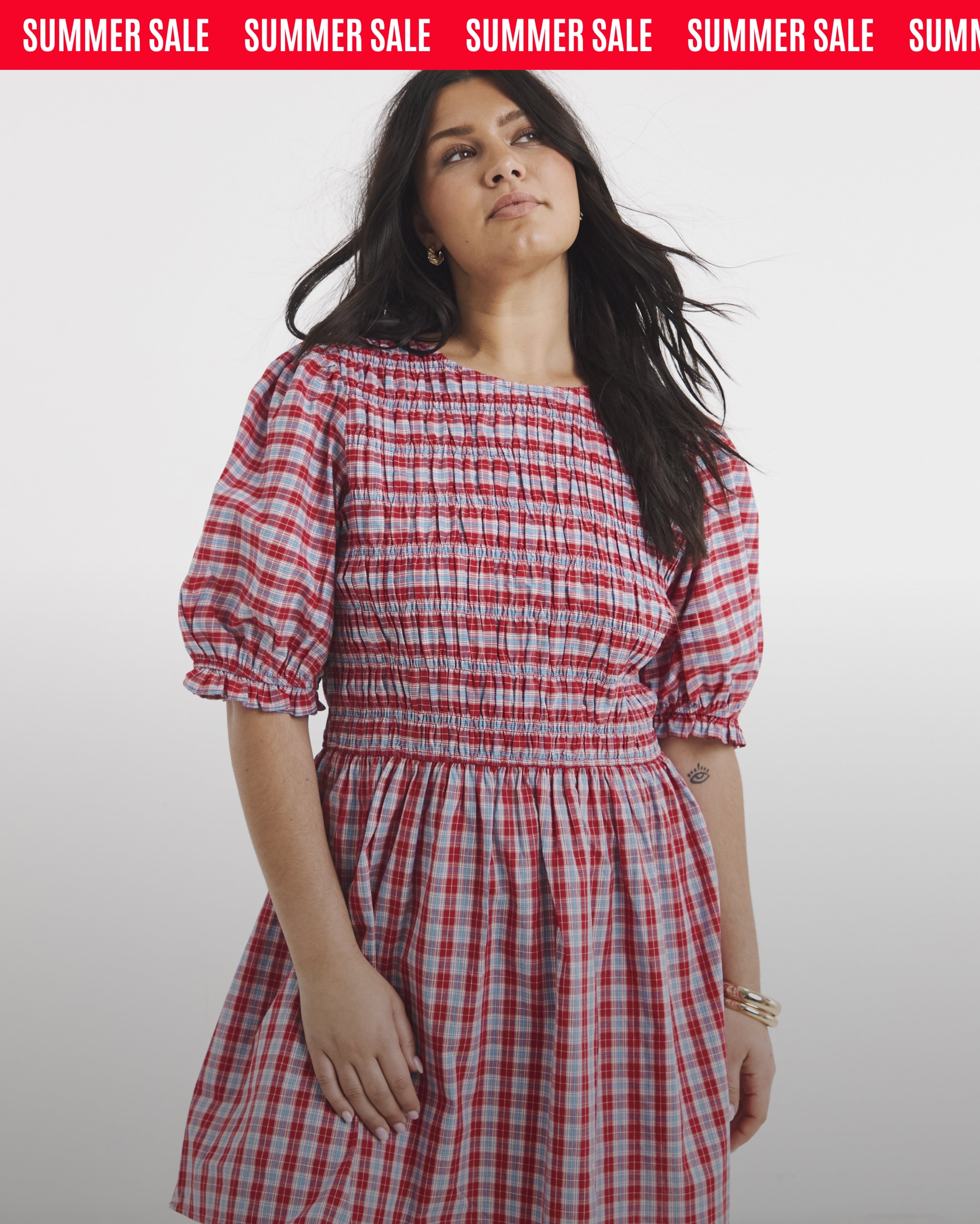 Summer sale banner featuring a person modelling a red and blue checked midi dress.