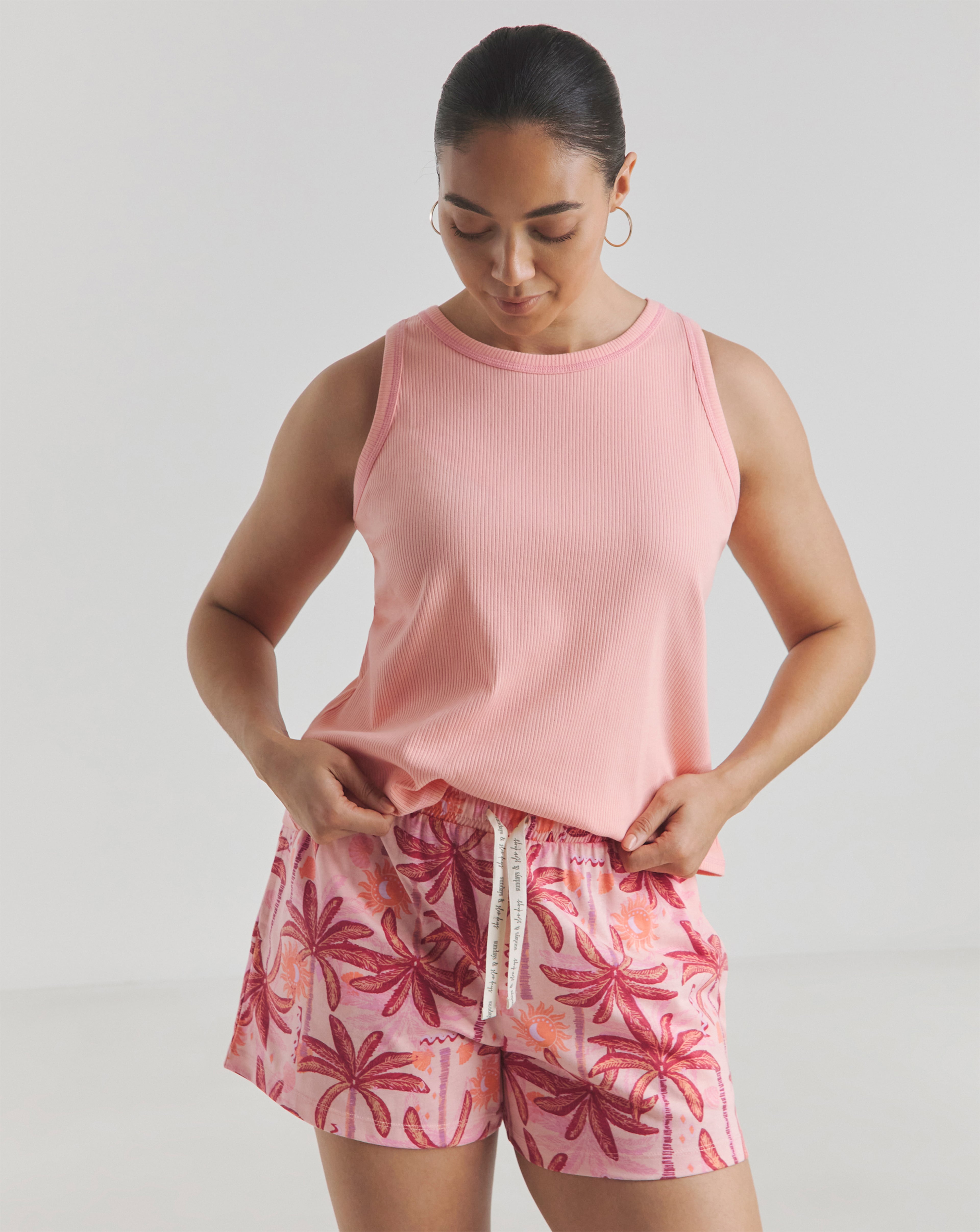 Person wearing a pink sleeveless top and patterned shorts with a tropical print.
