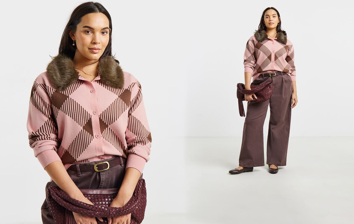 A person wearing a pink checked cardigan with a faux fur collar, brown trousers, and holding a woven burgundy handbag.