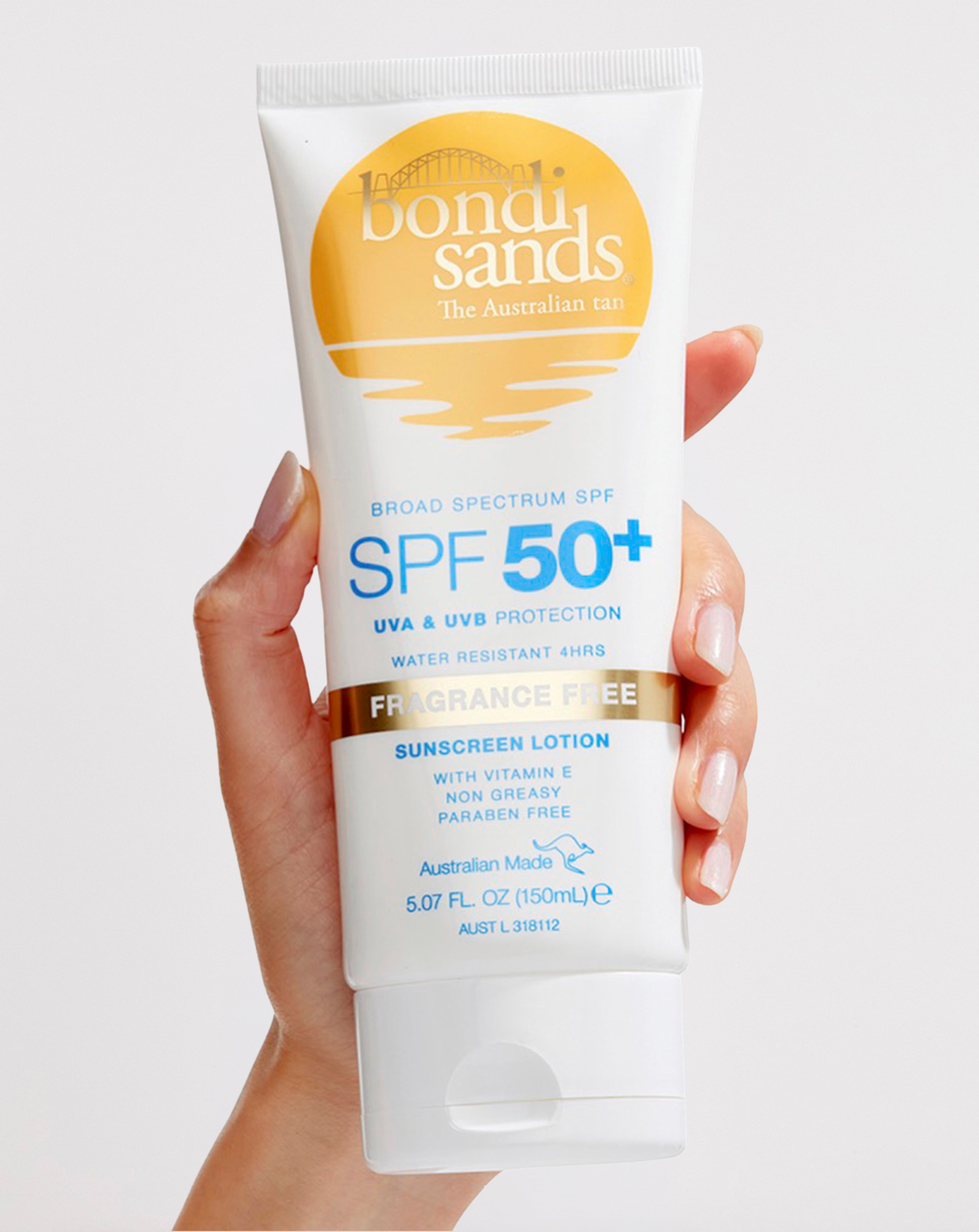 Person holding a tube of Bondi Sands SPF 50+ sunscreen lotion.