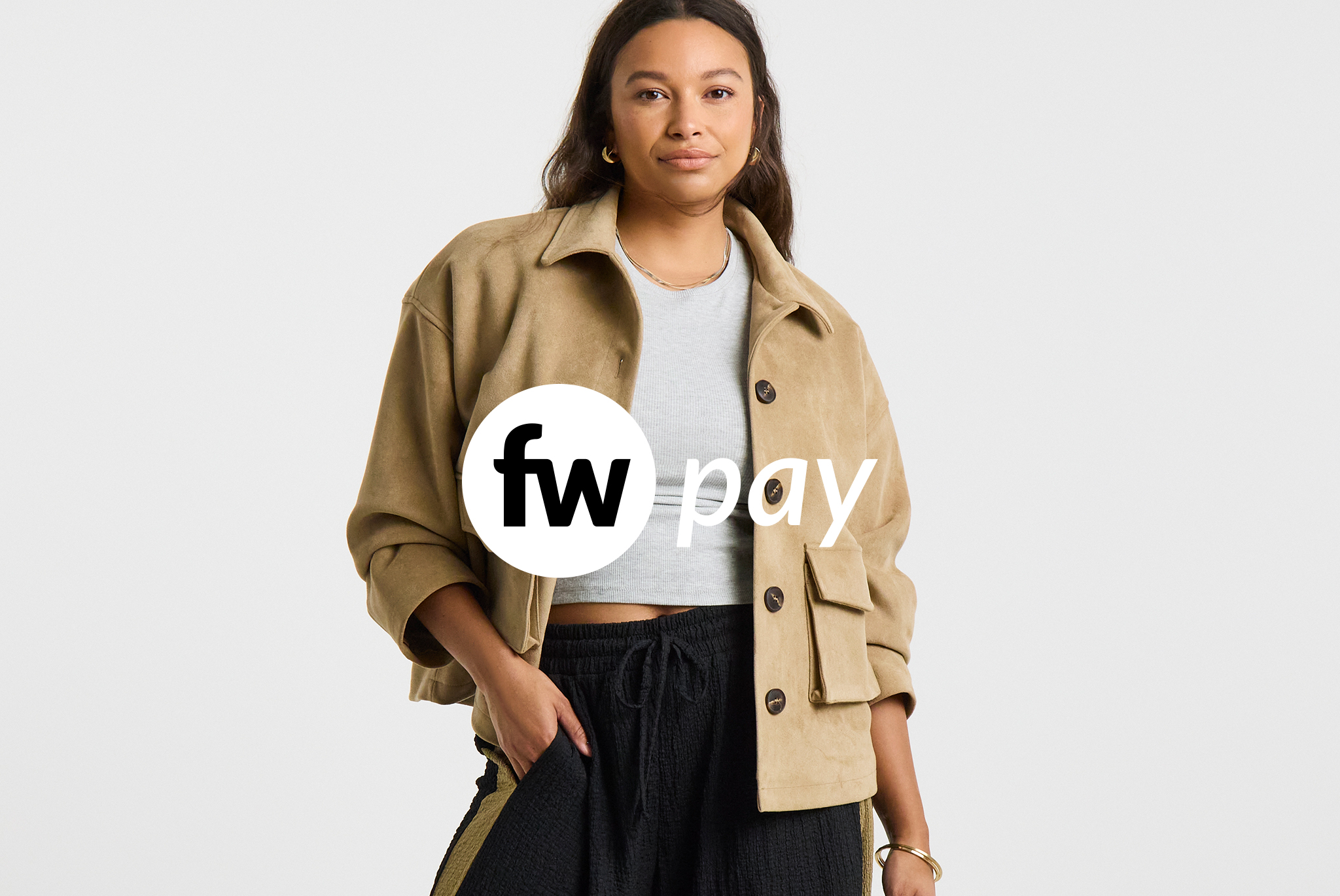 Person wearing a beige button-front jacket over a light grey cropped top and dark textured trousers, standing against a light grey background with the FW Pay logo overlaid.