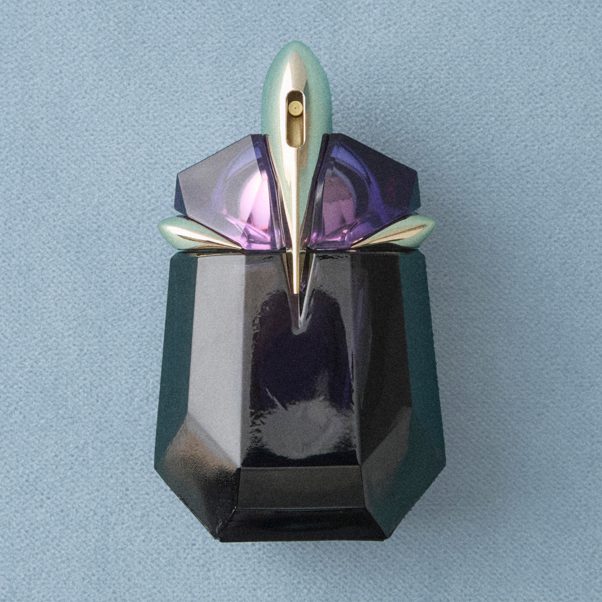 A dark green fancy glass perfume bottle