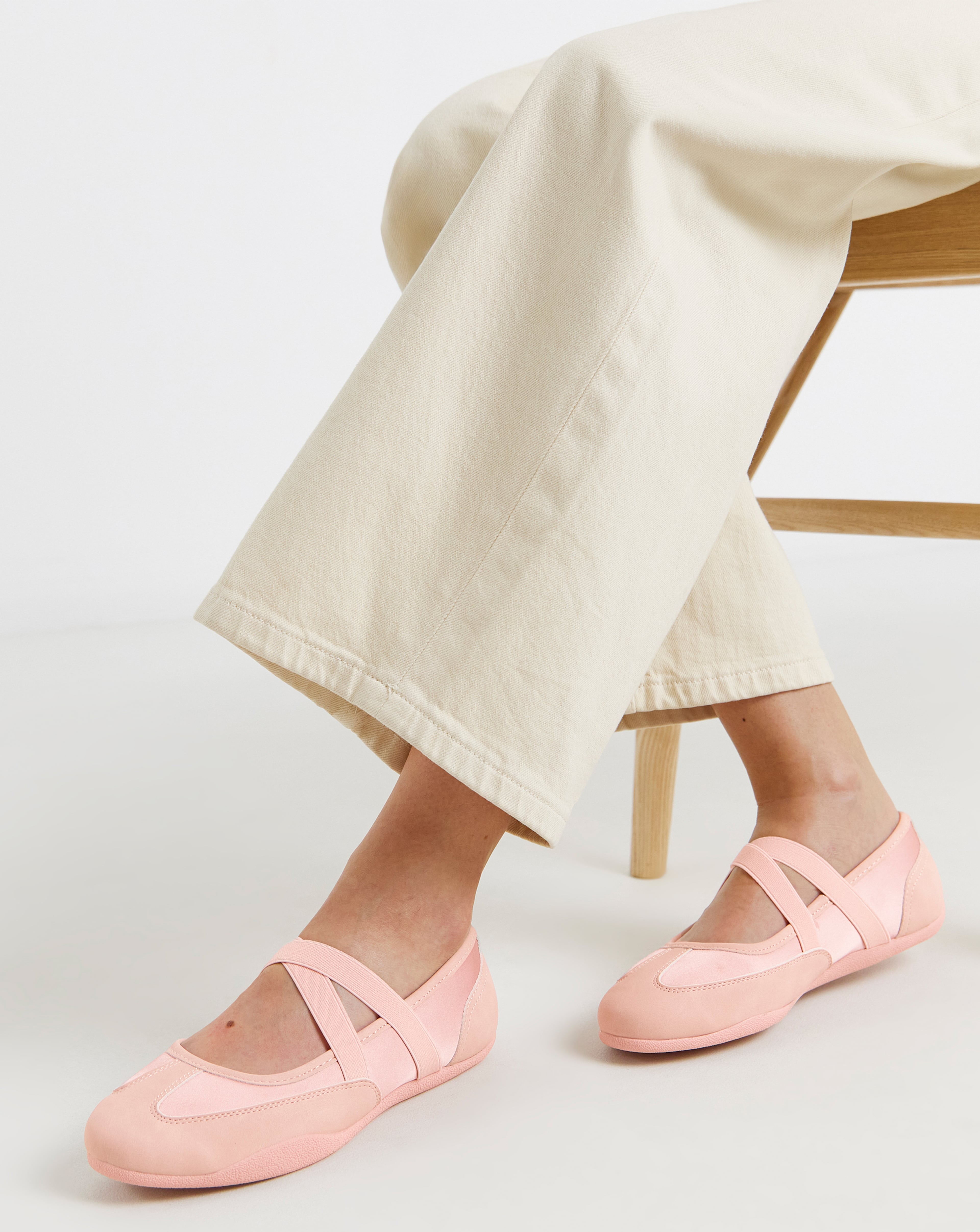 Close-up of a seated person wearing pink wide fit ballerina trainers.
