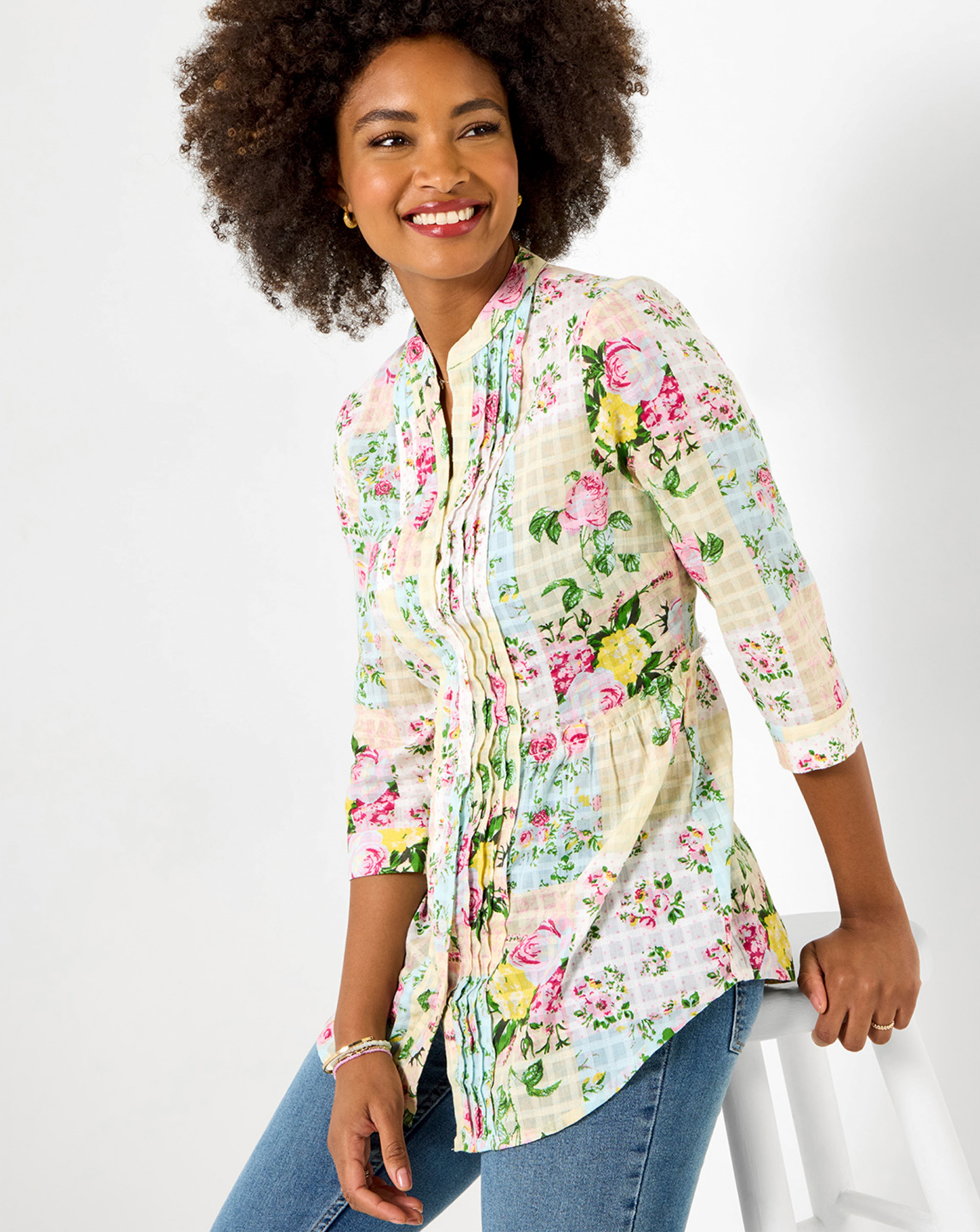 Person wearing a white Joe Browns shirt with a multi-coloured pattern, and blue jeans.