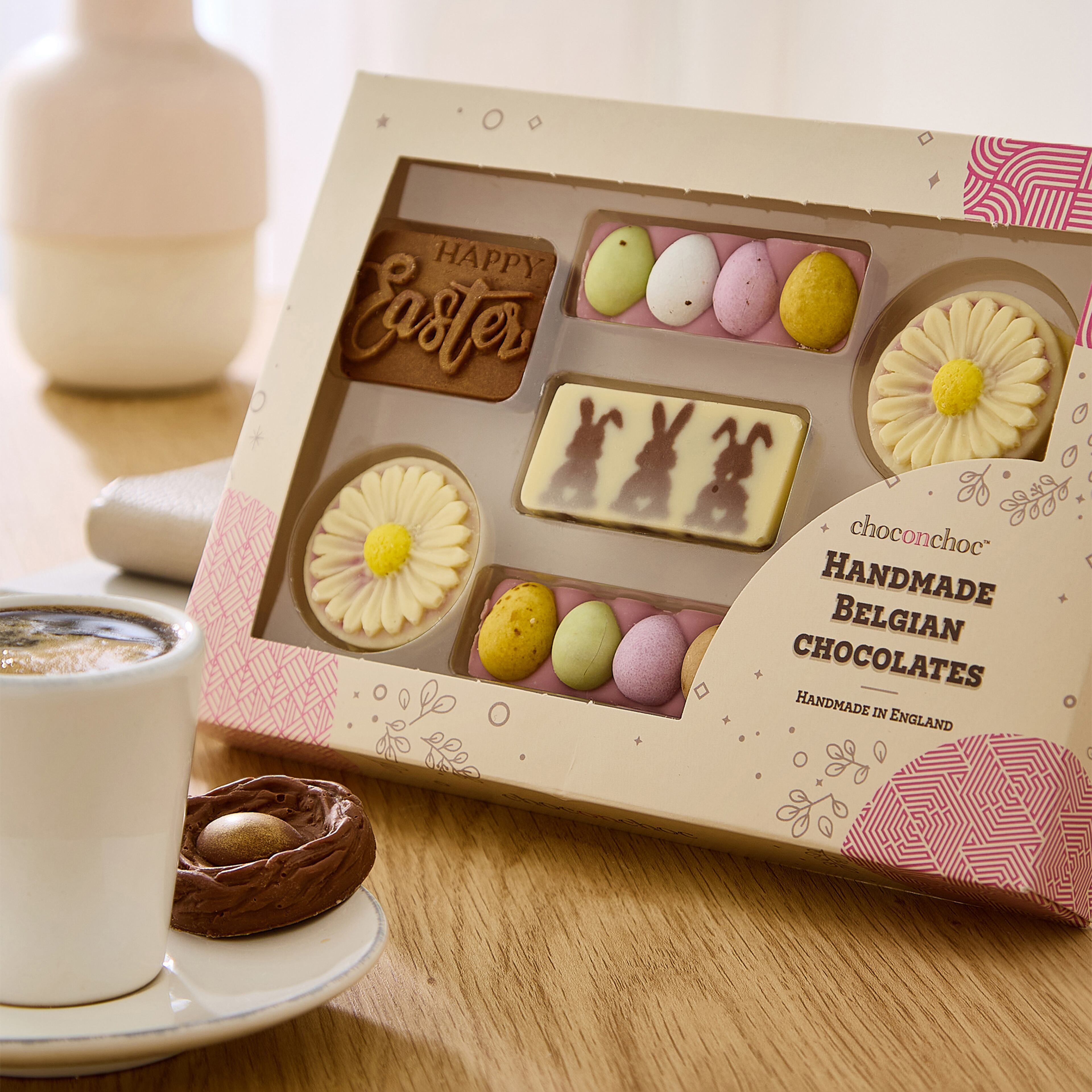 Choc on Choc Easter Selection Box displayed on a wooden table, with a cup of coffee.