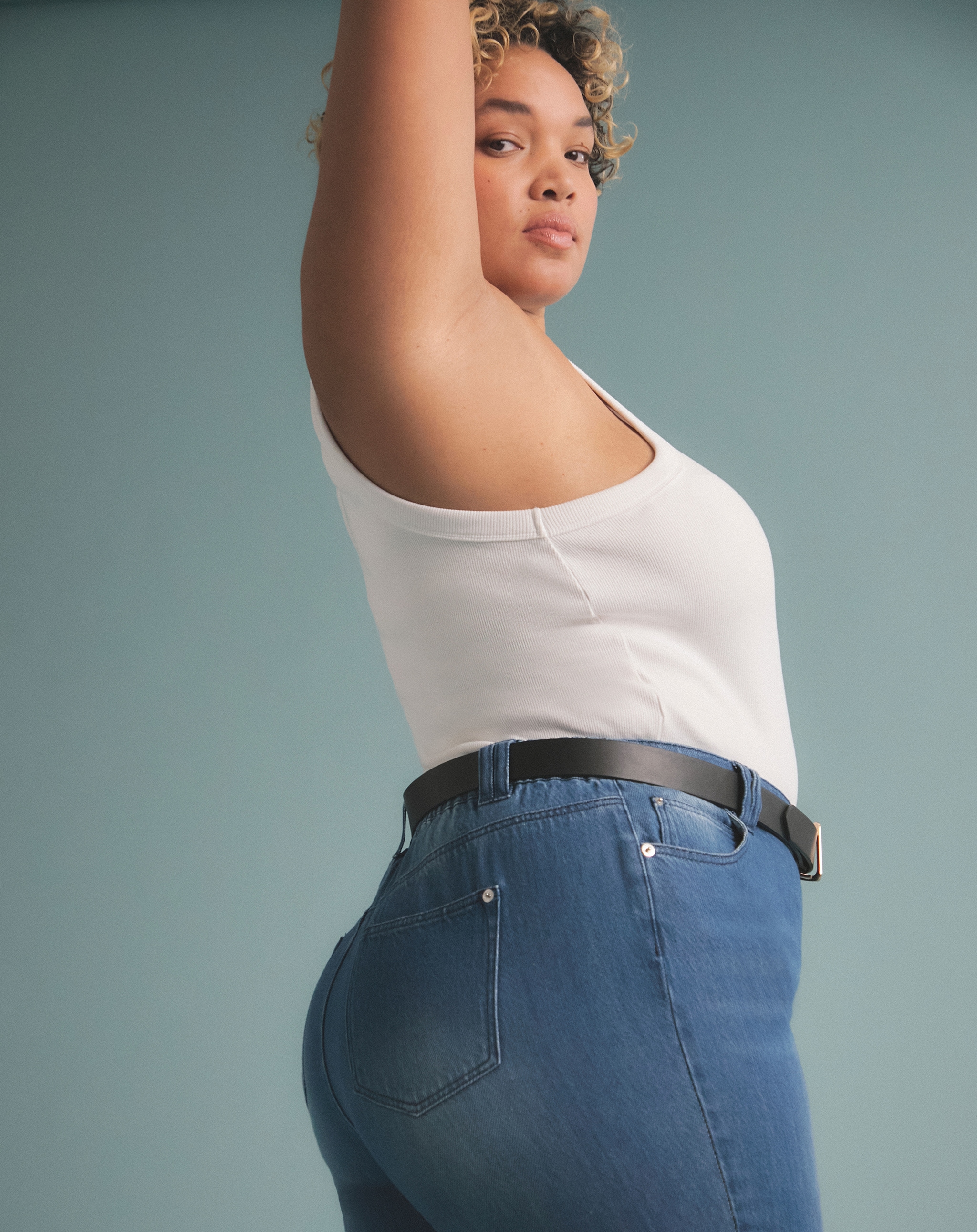 A woman wearing a mid blue pair of jeans and white vest
