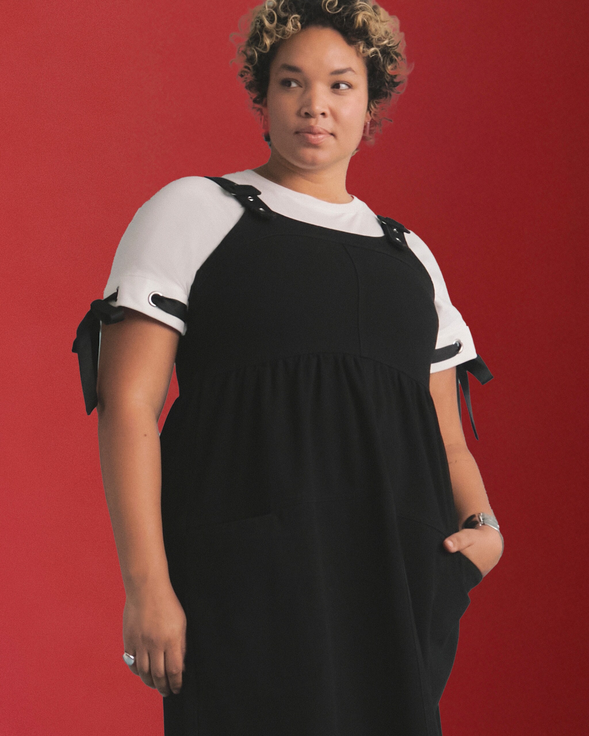 A woman wearing a black dress over a white shirt.