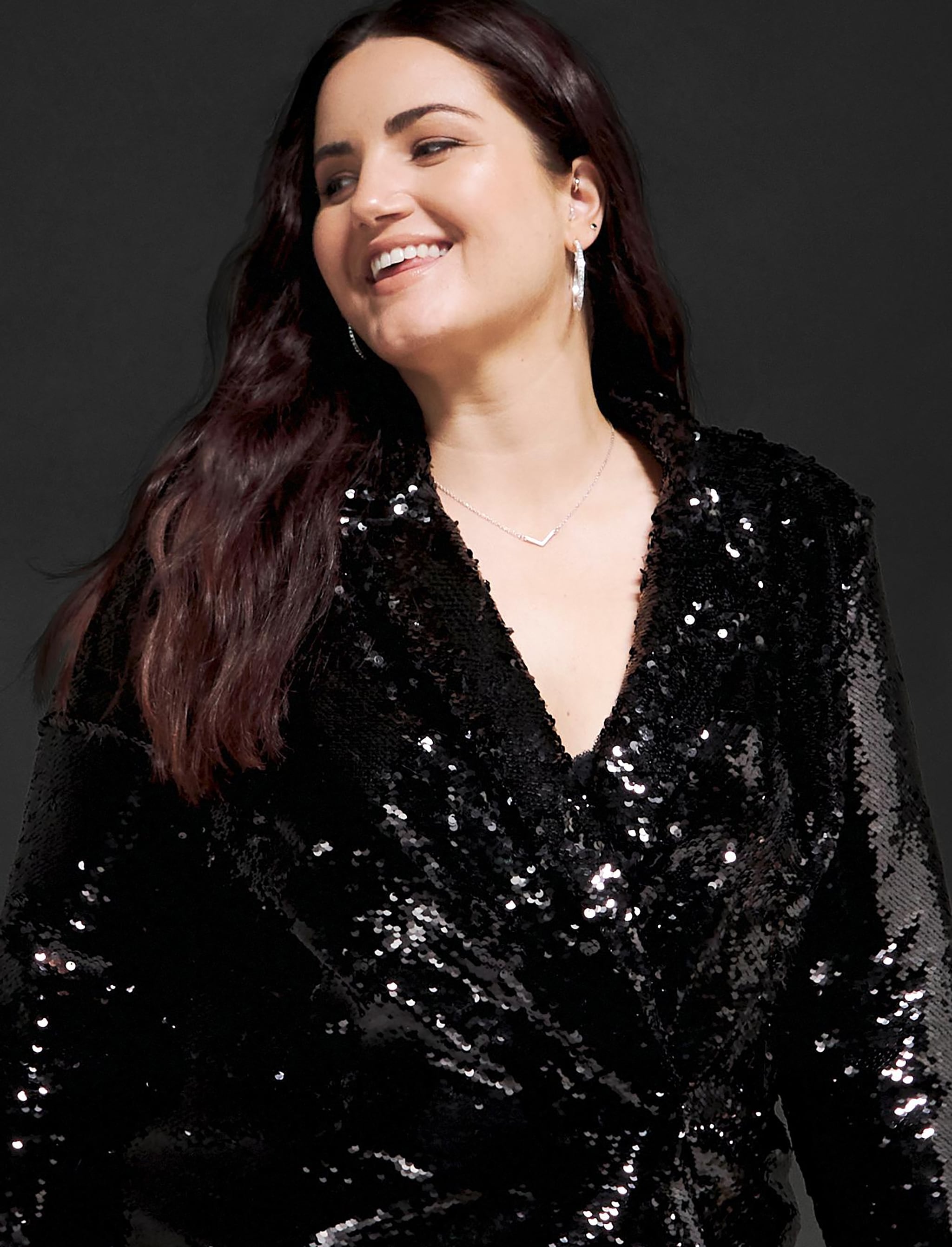 A woman stood wearing a long sleeved sparkly black shirt