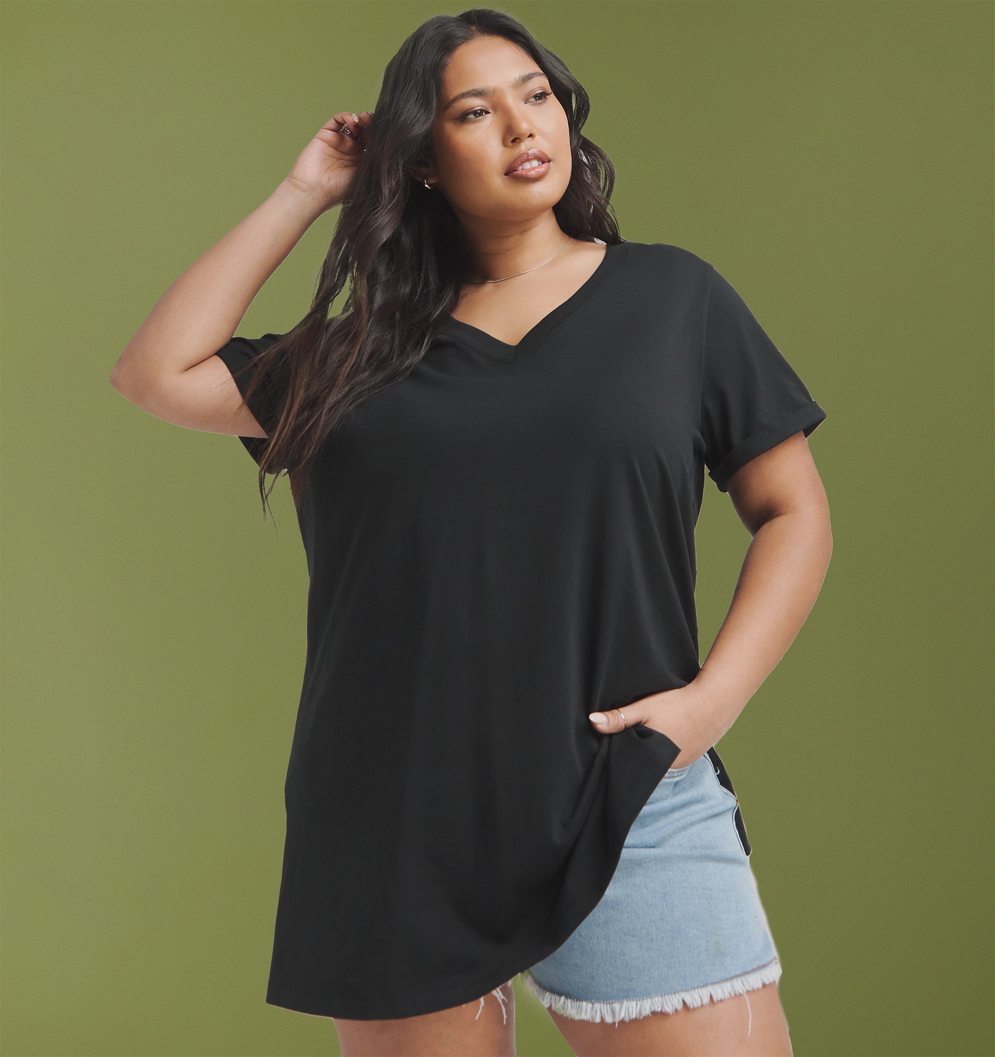 A woman stood wearing a black t-shirt and denim skirt