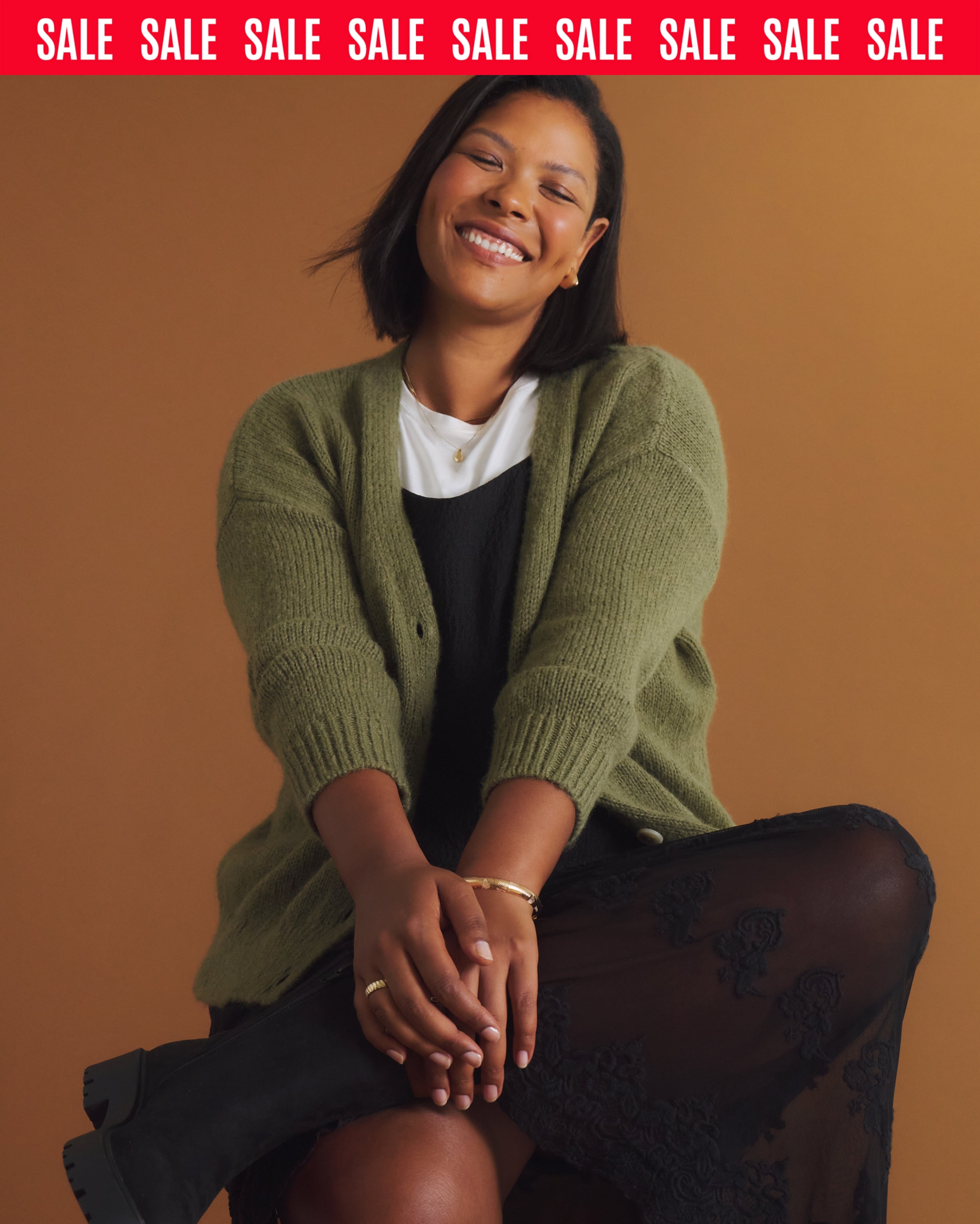 Joyful Woman Seated in Green Cardigan Portrait With Warm Brown Studio Backdrop