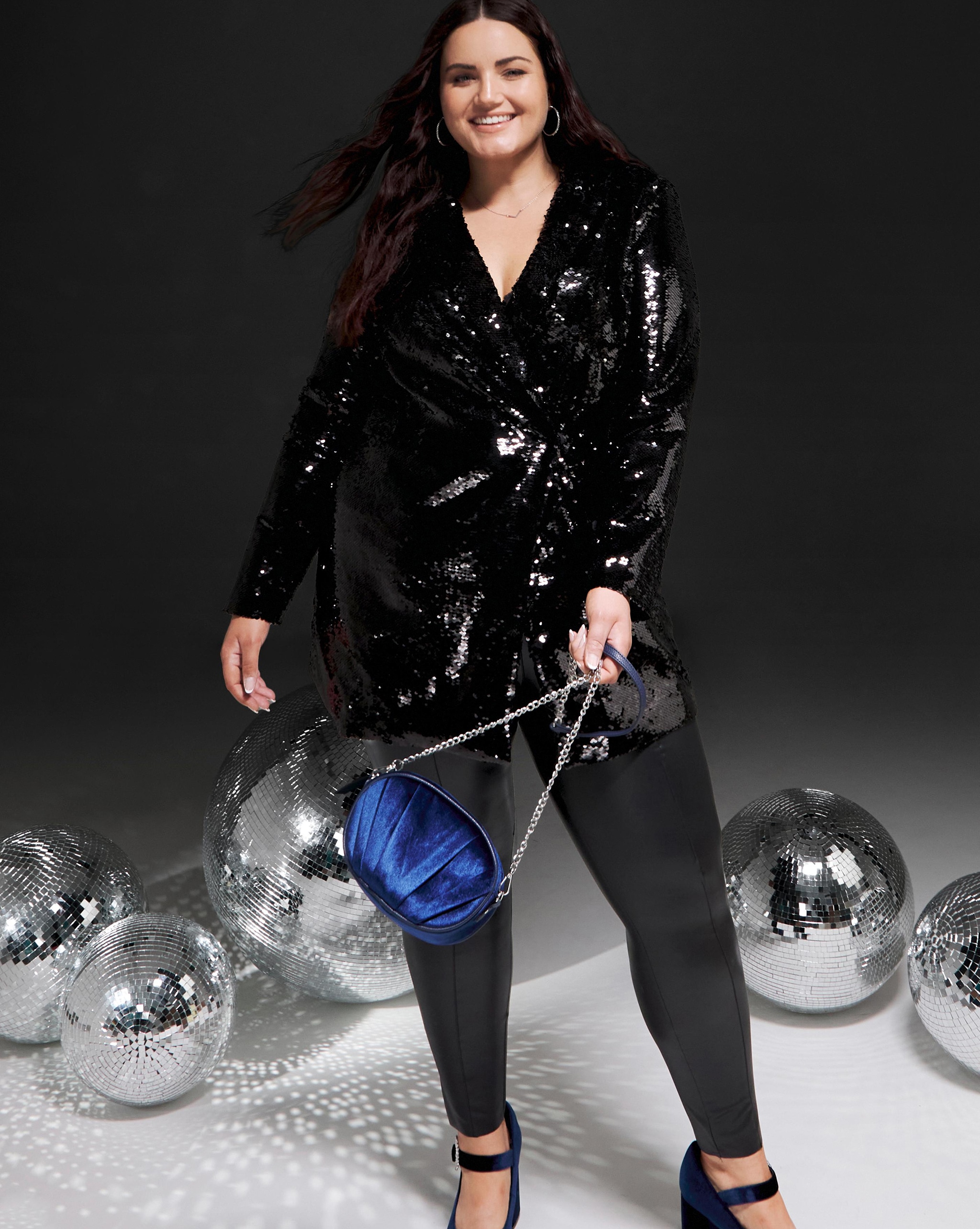 A woman stood wearing a long sleeved sparkly black shirt