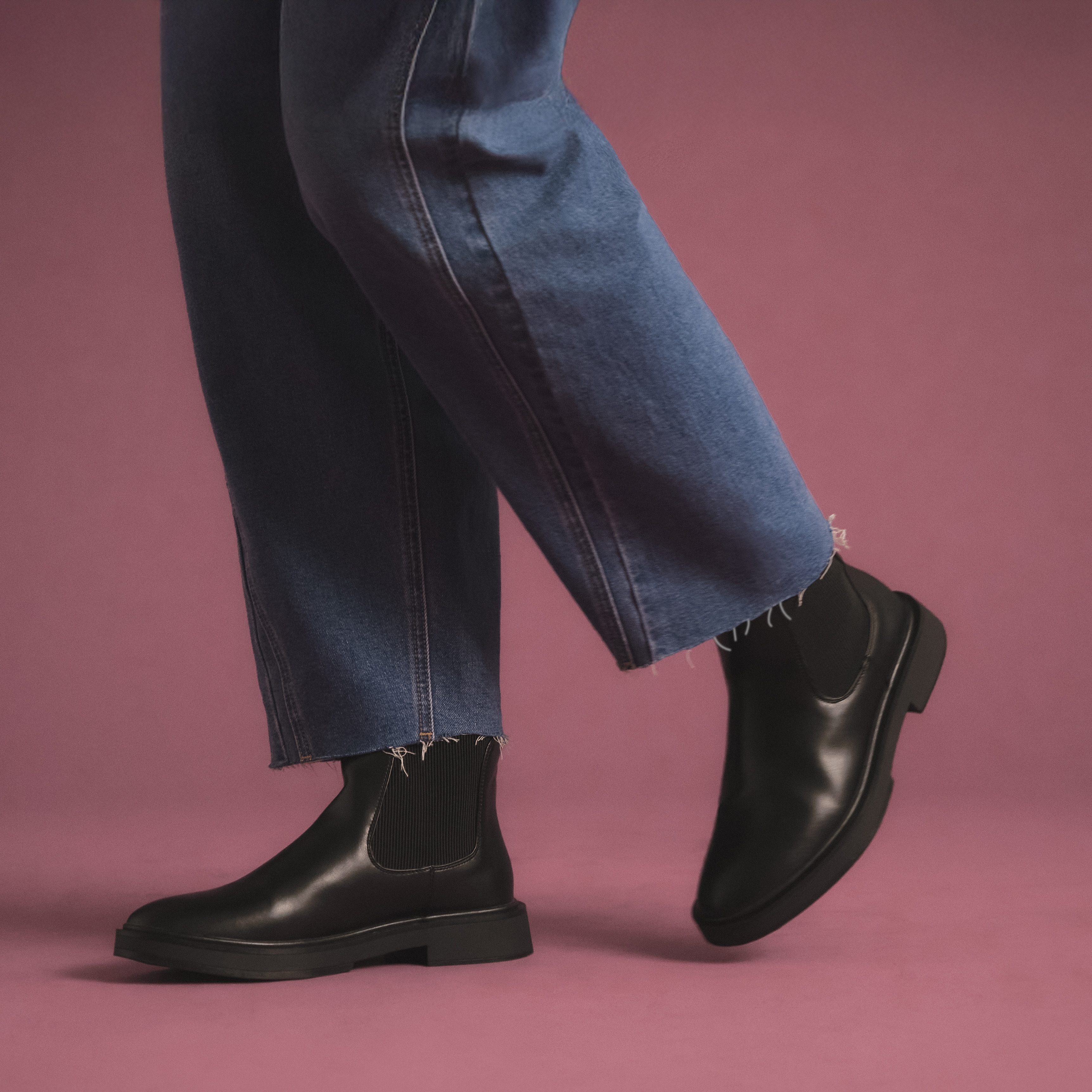 A model wearing wide fit jeans and black Chelsea boots