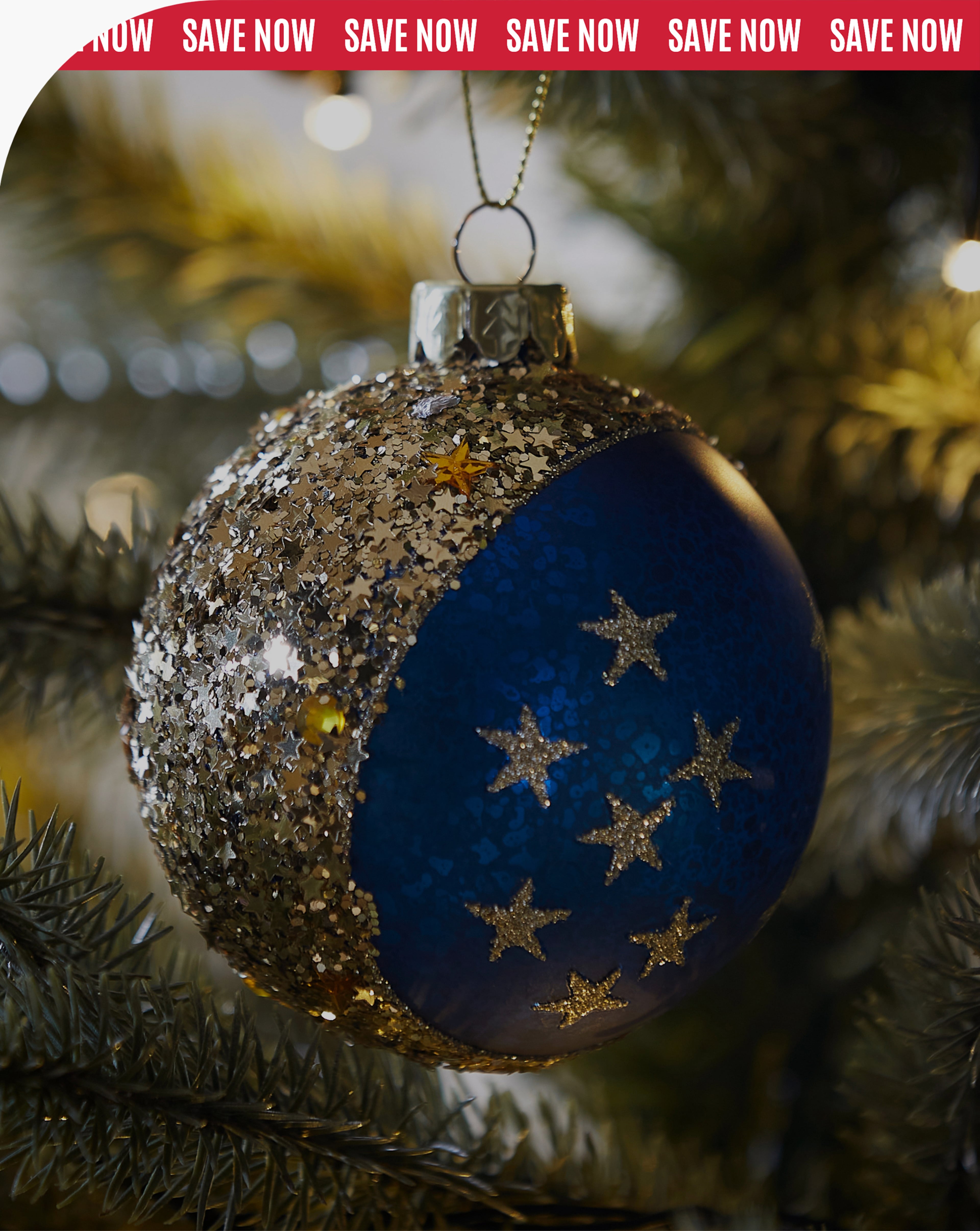 A close-up of a round Christmas bauble hanging from a branch of a Christmas tree.