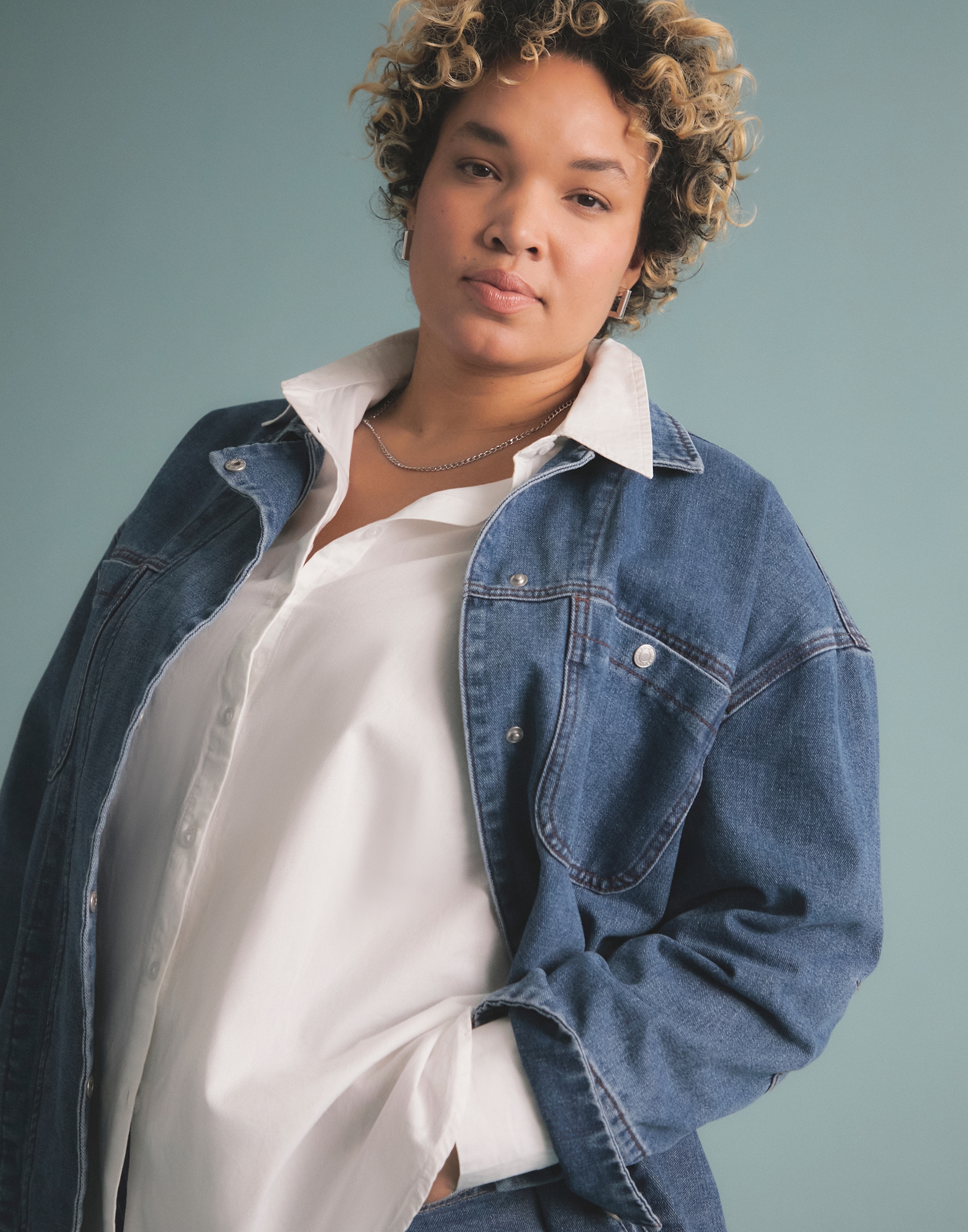 A woman wearing a denim jacket over a white blouse