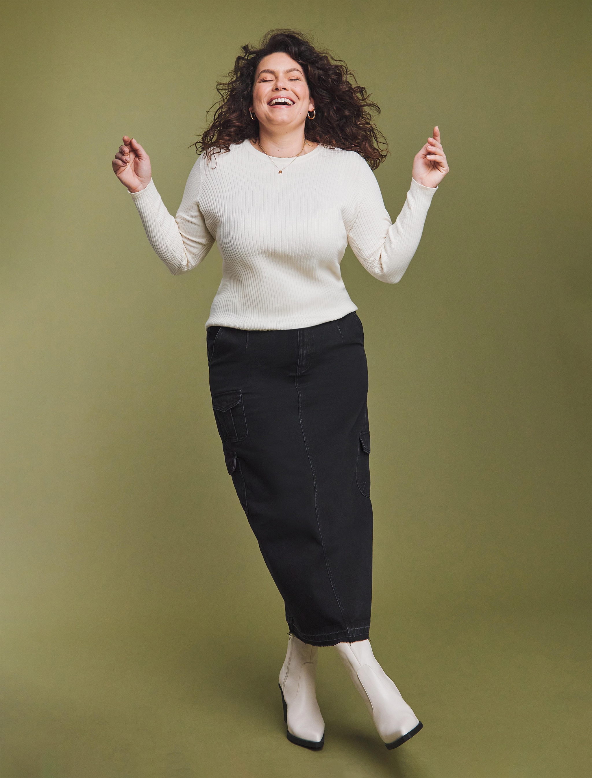A woman stood wearing a fitted white pullover and black 3/4 length black trousers