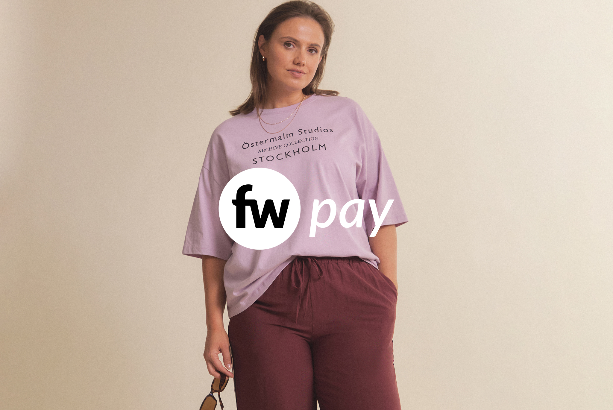 A confident woman stands wearing a stylish lavender t-shirt and maroon trousers.